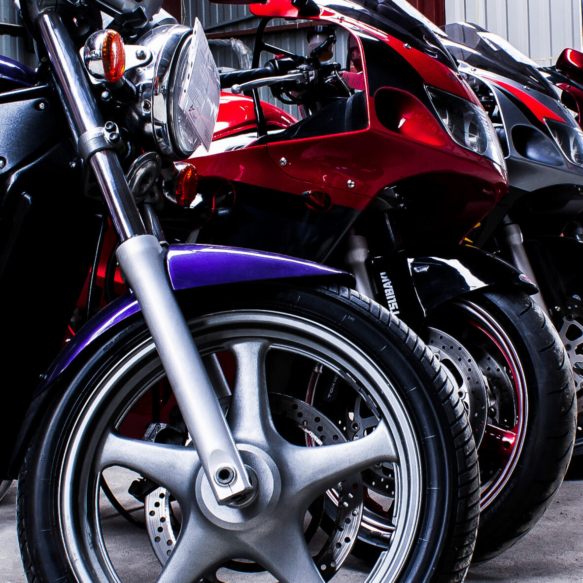 Colored sports, road beautiful bikes in a motor show, close up. Many motorcycles parked in a store. Sale of used cruise motorbikes in the cabin. Showroom equipment in the garage. Banner for web site