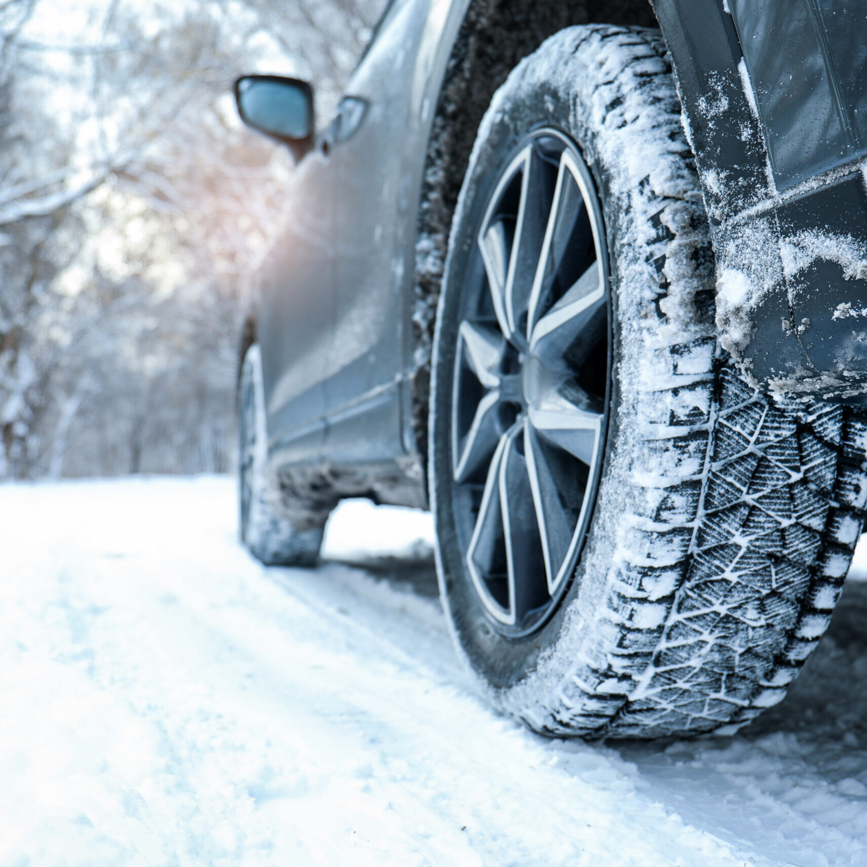 Snowy country road with car on winter day, closeup. Space for text
